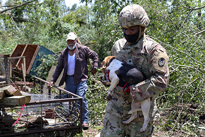 Spc. Antonio Hall, with the North Carolina Army National Guard’s 882nd Engineer Company, 105th Engineer Battalion, helps a resident gather his dogs after Hurricane Isaias had made its way through Windsor, North Carolina, Aug. 4.
